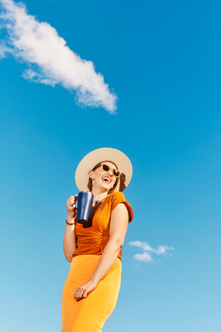 woman smiling with coffee tumbler.